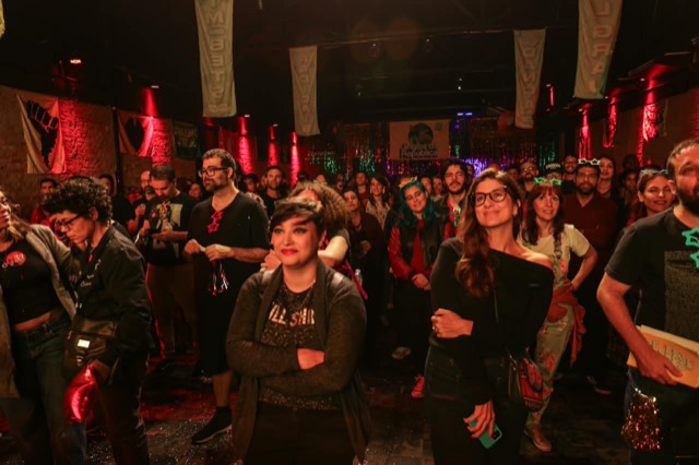 Público de pé, olhando para o palco.