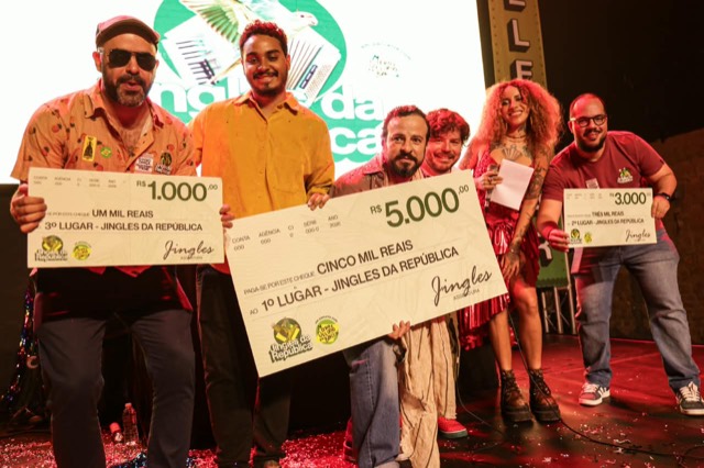 Premiados lado a lado no palco com os cheques de R$ 1.000, R$ 5.000 e R$ 3.000.